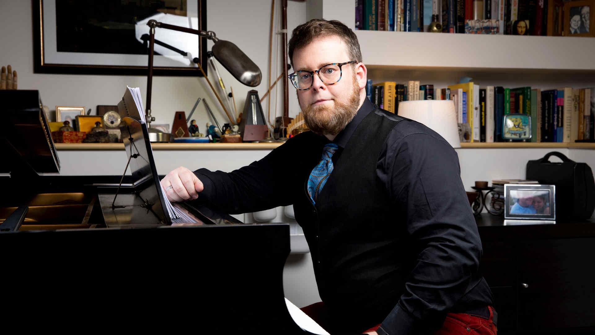 David Ludwig seated at piano in a posed professional headshot