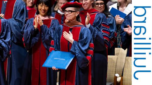 older woman holding a diploma on a stage